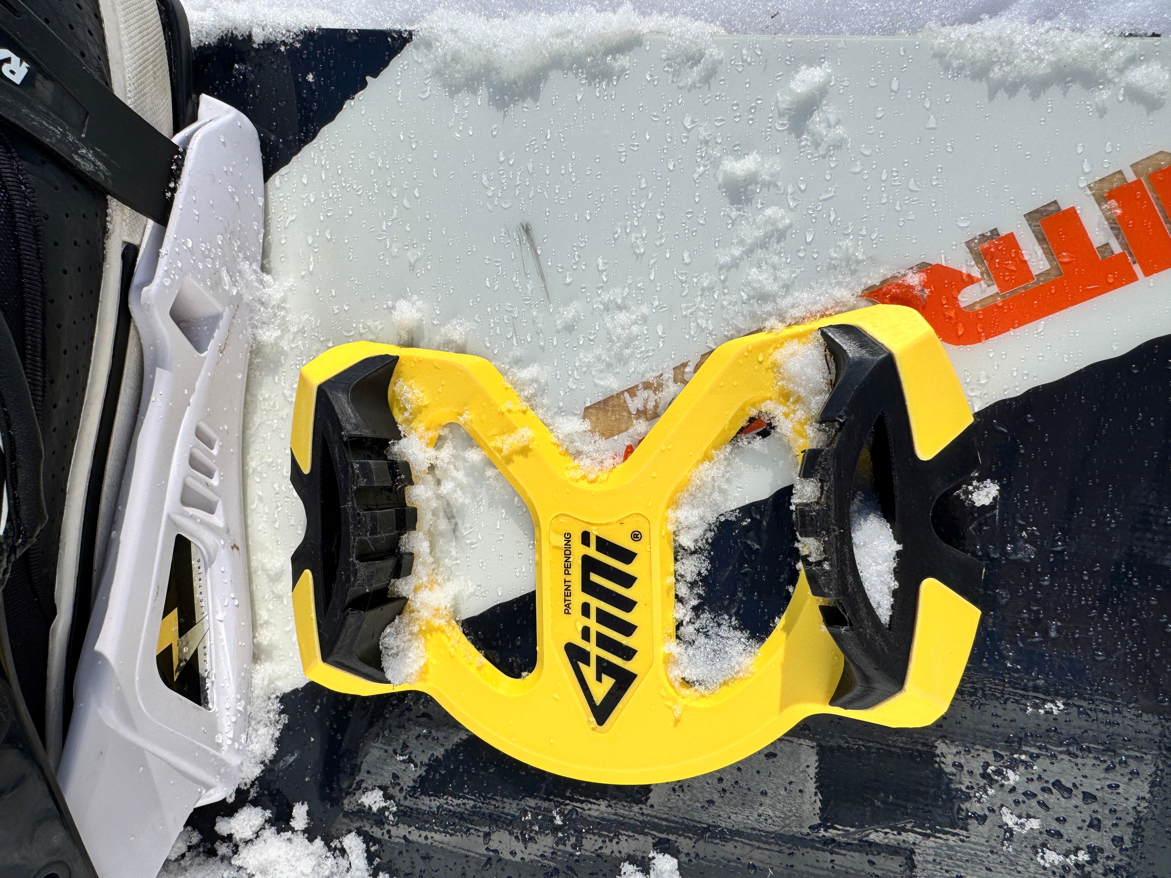 Giini Pyro Hazard yellow stomp pad mounted on a snow-dusted Nitro snowboard, top-down close-up
