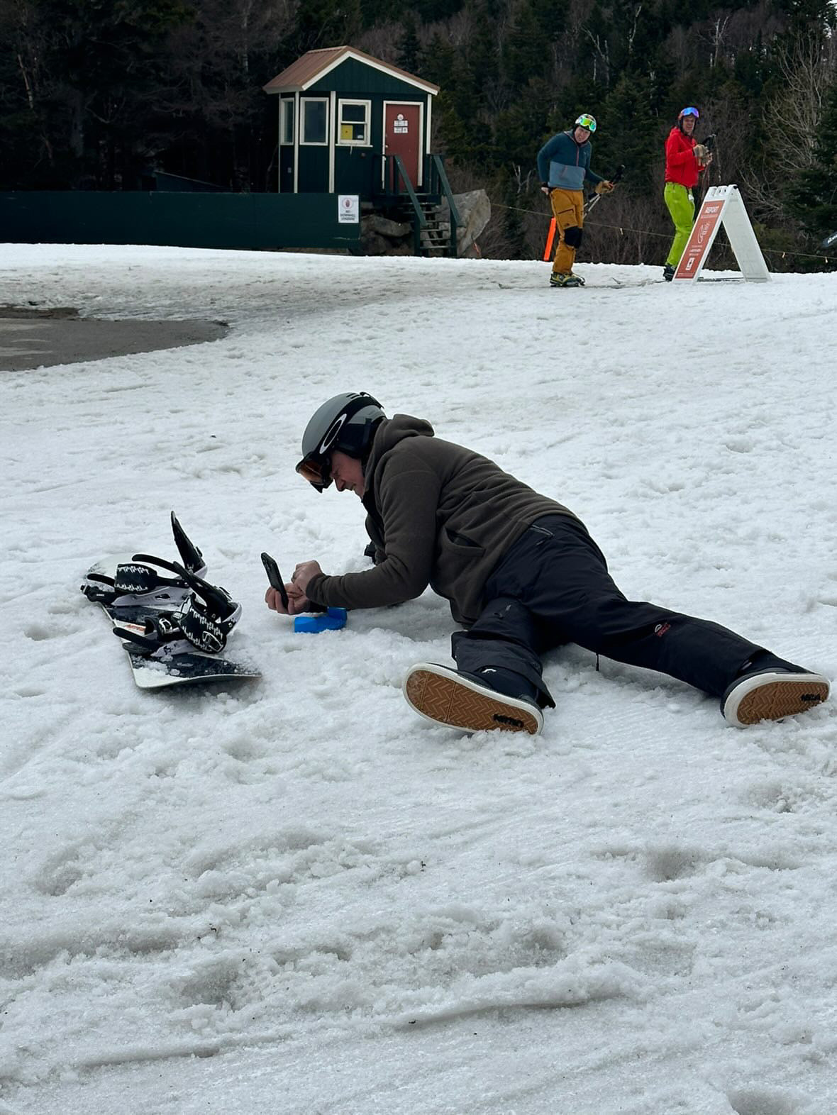 Rider crouched over a snowboard on the snow at the base area, fitting a Giini Pyro