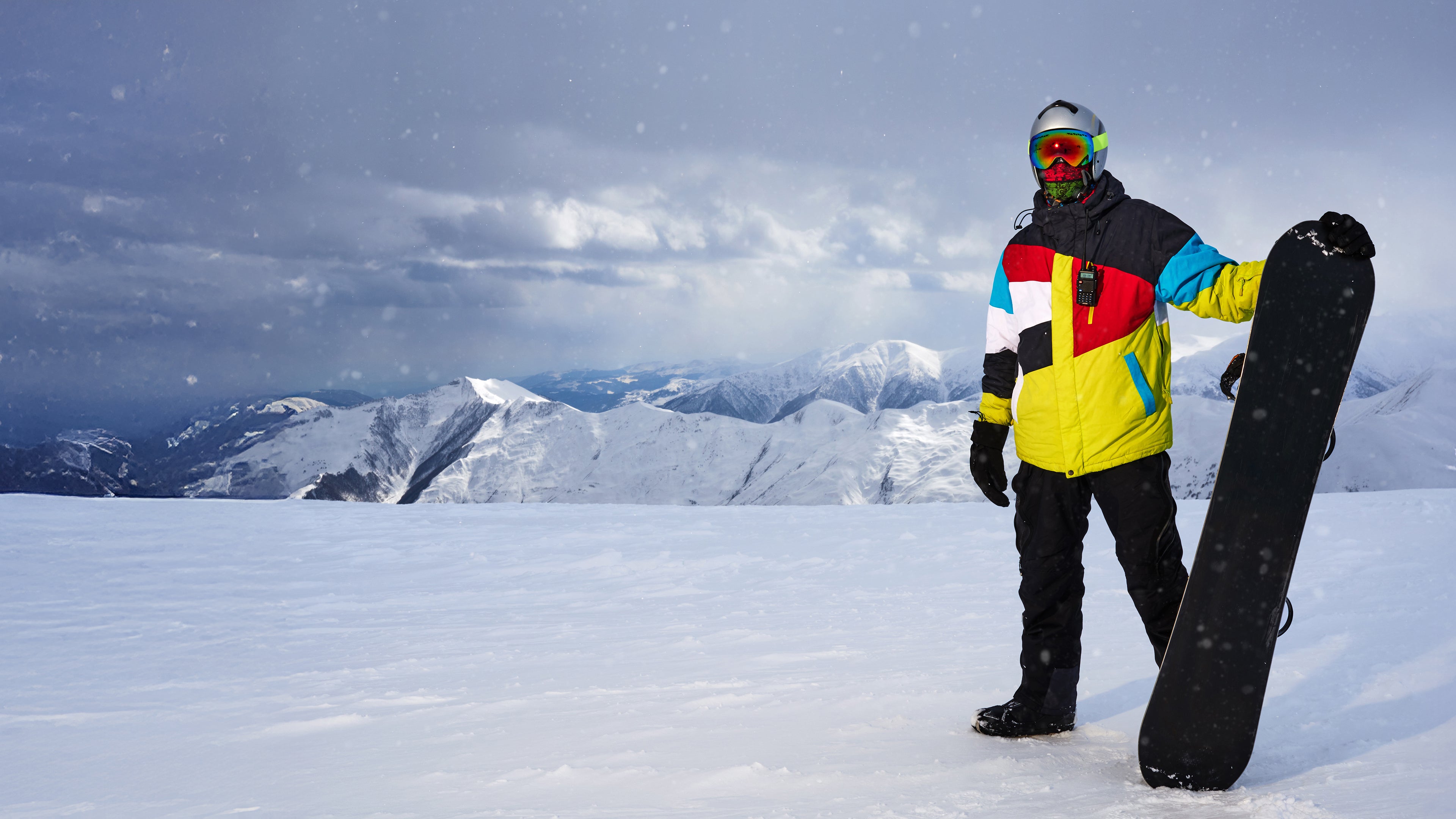 Snowboarder standing on a mountain summit, wide banner with copy space