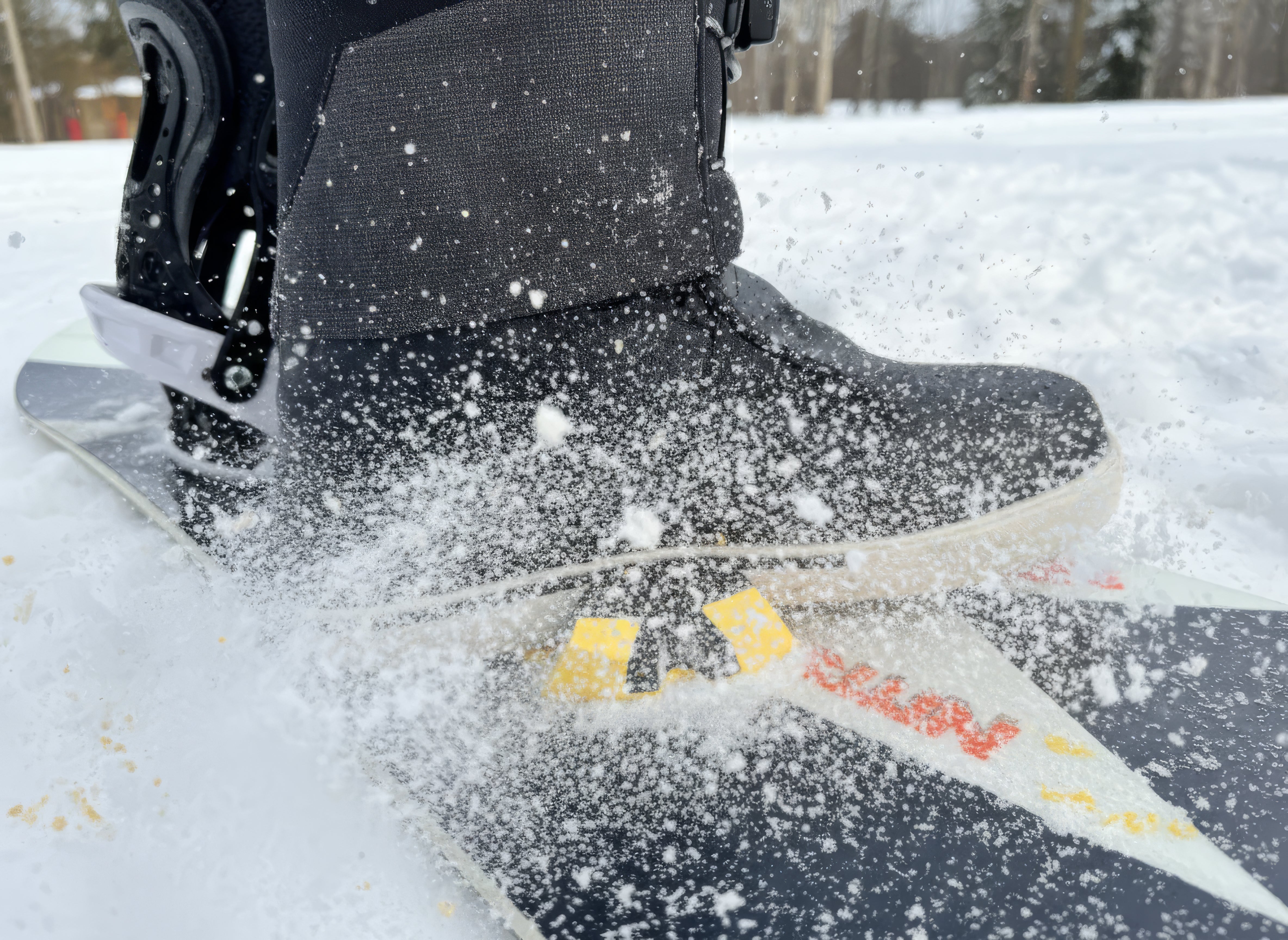Person snowboarding with a focus on the boot and board in a snowy setting